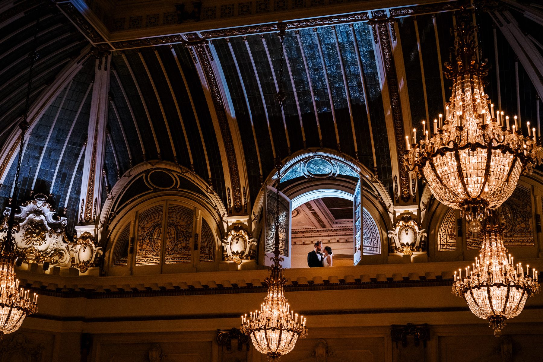 Newlyweds framed by Garden Court chandeliers at The Palace Hotel in San Francisco
