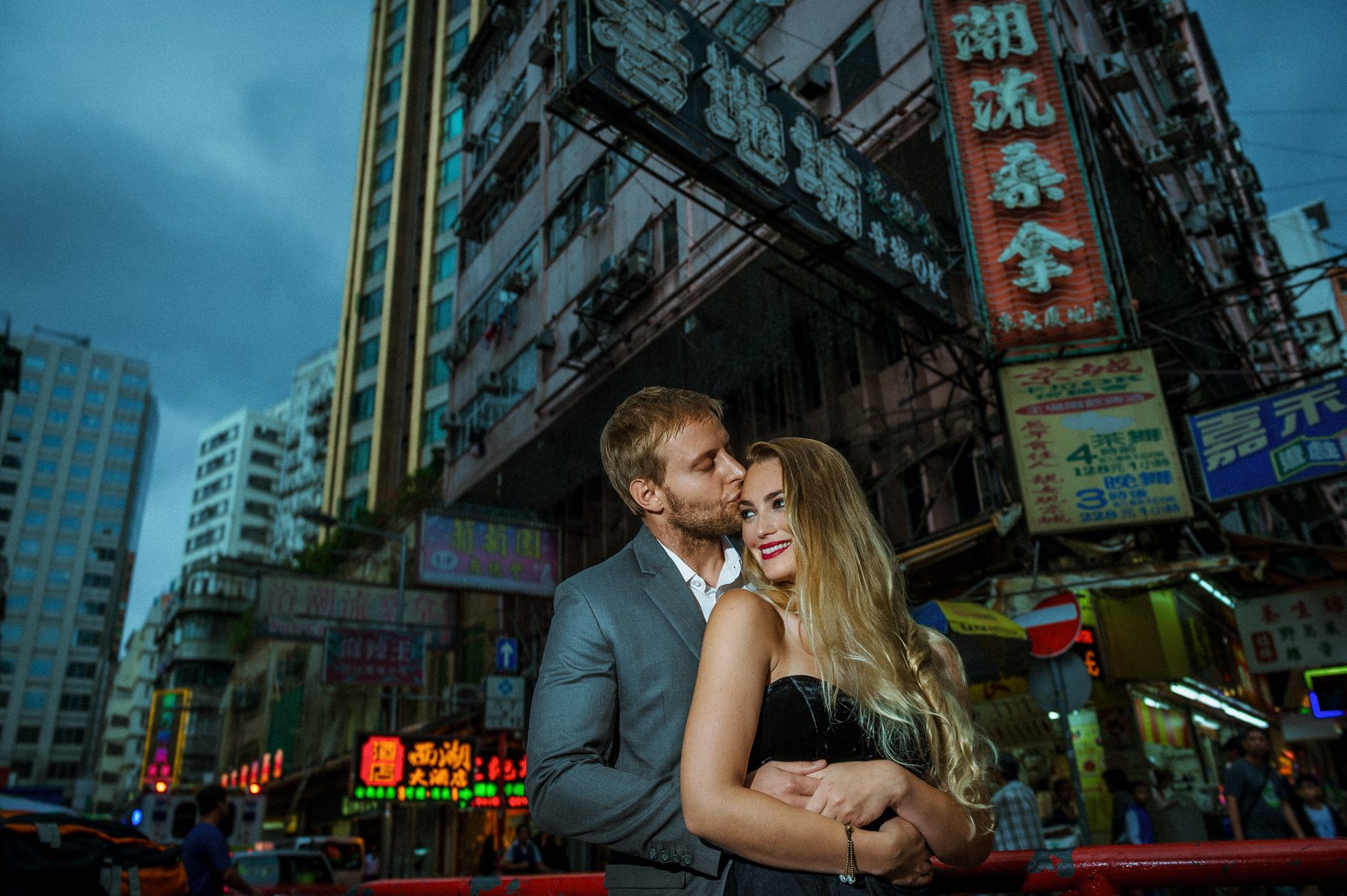 Engaged couple embracing among neon signs in Kowloon during a Hong Kong engagement session