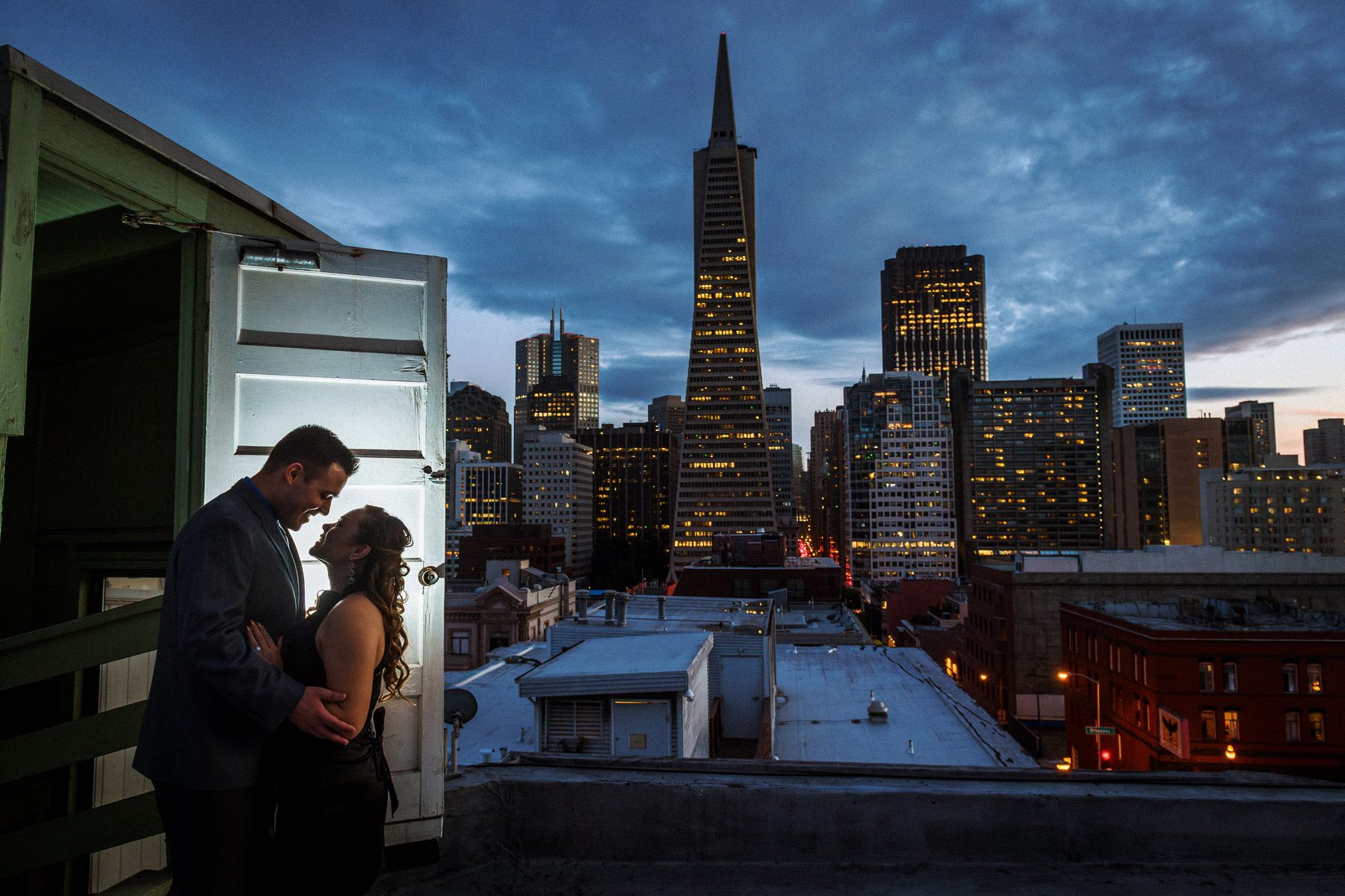 Engaged couple on a rooftop with the Transamerica Pyramid during a San Francisco engagement session