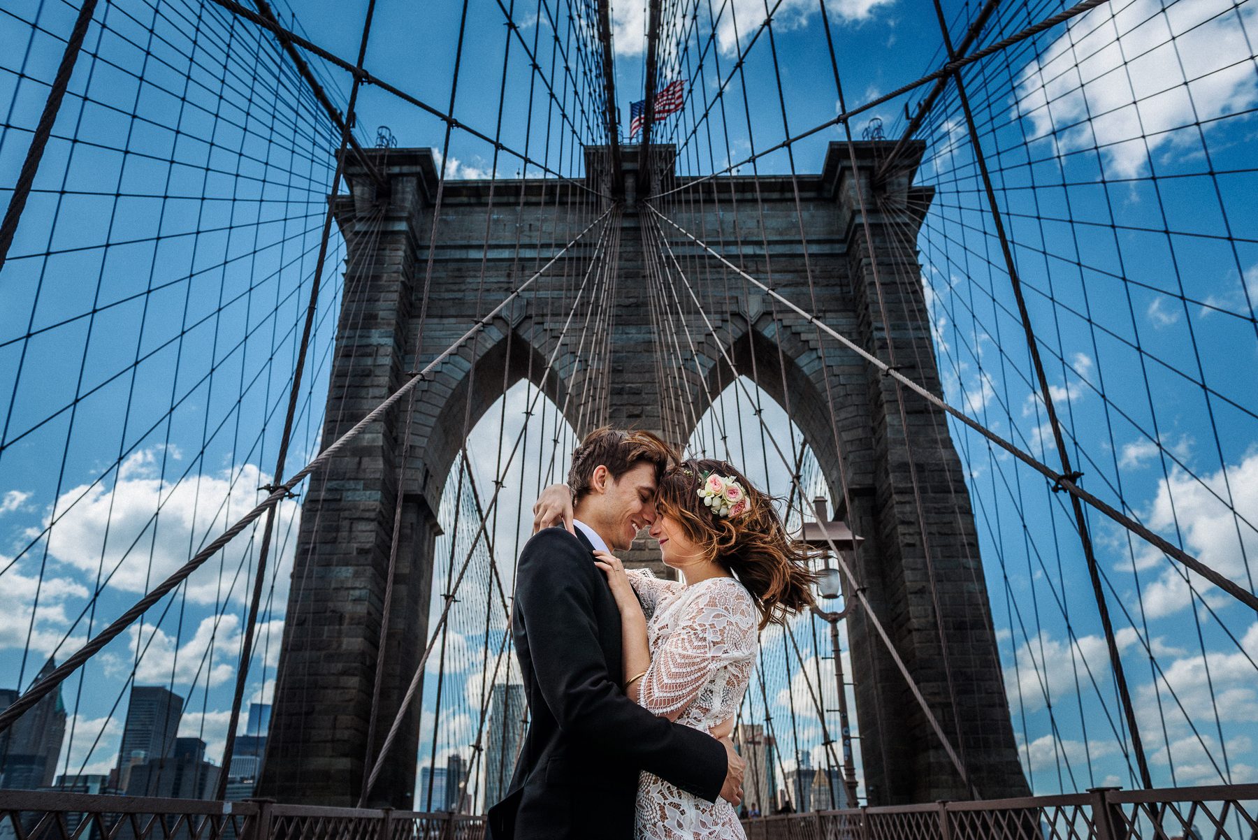 Bride and groom embracing beneath the Brooklyn Bridge during their New York wedding portraits