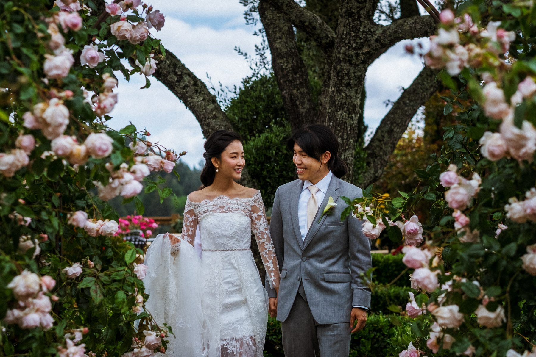 Bride and groom walking through a rose garden at their Regale Winery wedding in Los Gatos
